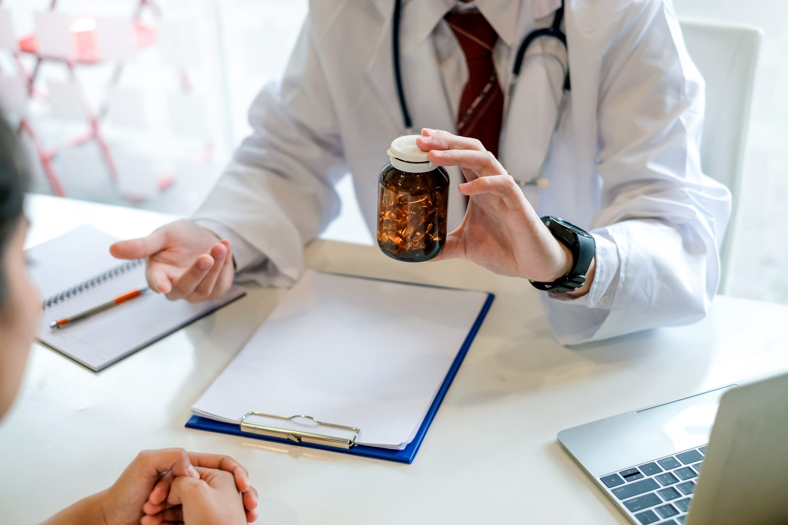 Onsite Medication Dispensing: Medical provider at desk shows pill bottle to patient