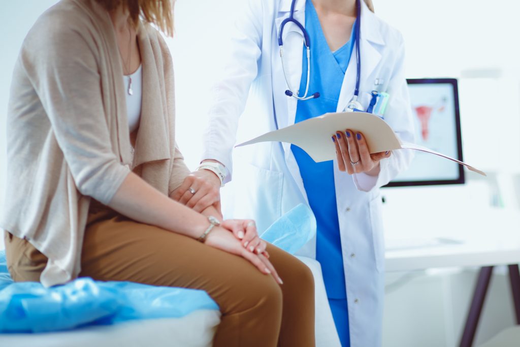 Women's Health: Medical provider gently touches female patient in exam room